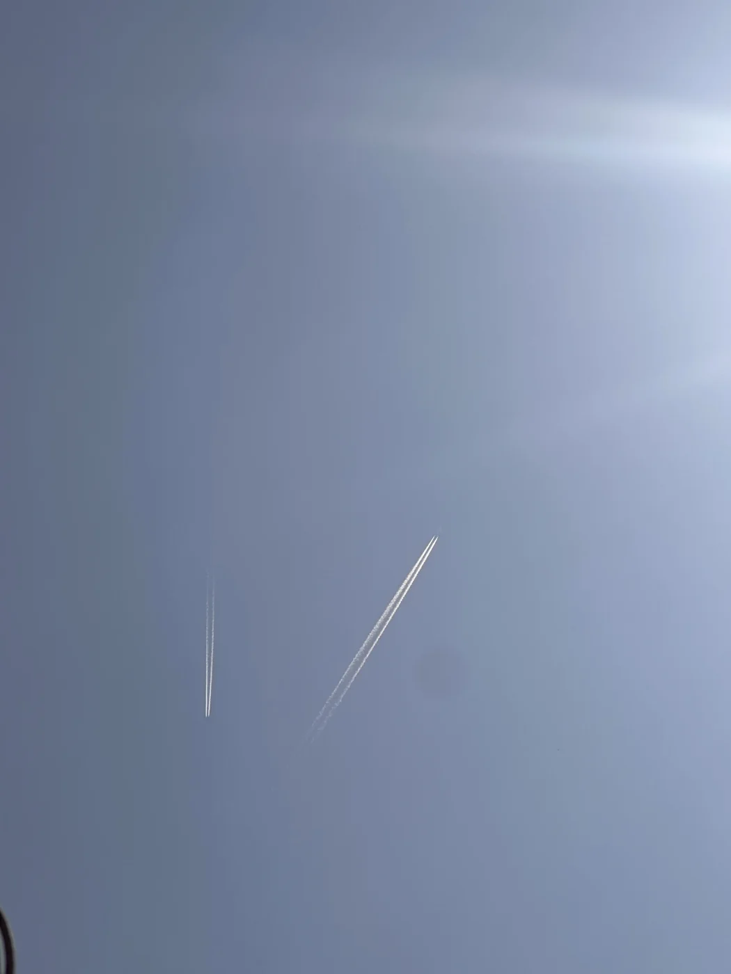 Two aircraft leaving white contrails across a blue sky